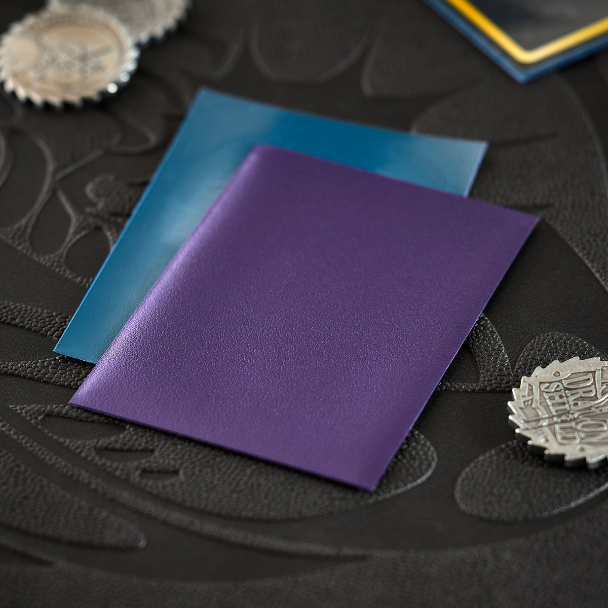 Matte card sleeves in blue and purple on a dark playmat